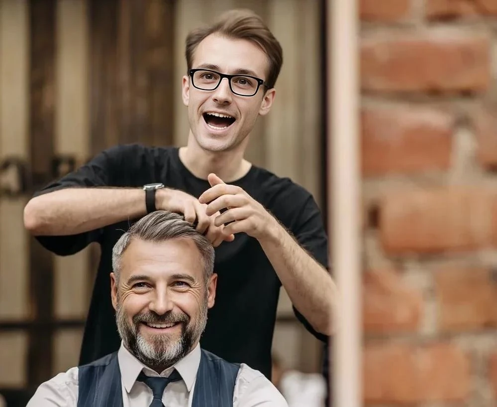 A man is getting his hair combed by another man.